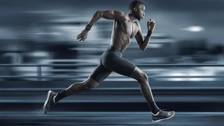 Atleta masculino correndo com bermuda térmica preta em uma paisagem urbana desfocada, destacando movimento e velocidade.